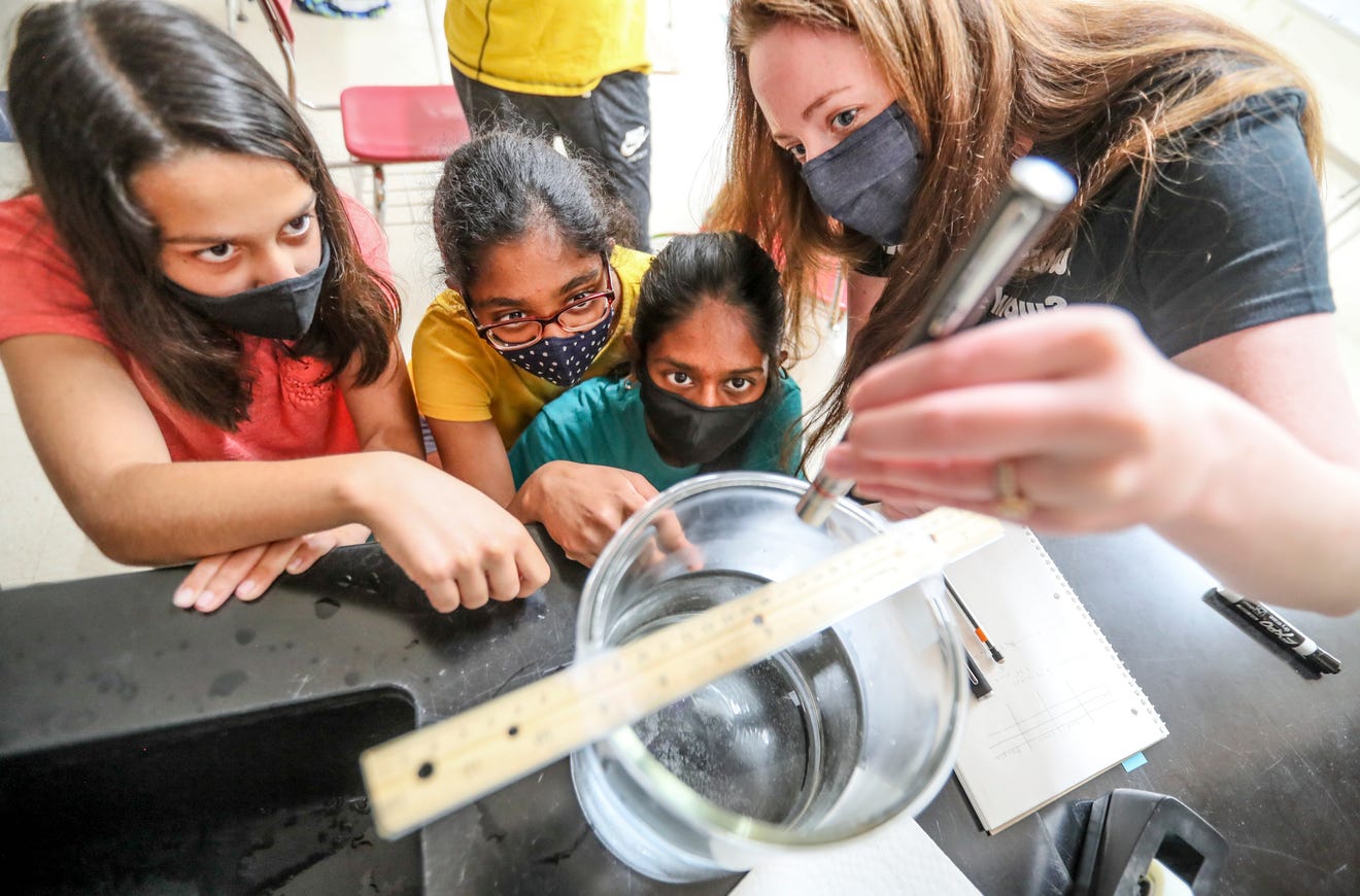 A teacher with a group of students looking at an experiment